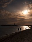 Les gens sur la plage au coucher du soleil — Photo de stock