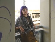 Mode stilvolle Frau mit lila Frisur schaut weg und lehnt sich an Geländer — Stockfoto