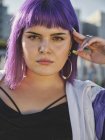 Fashion woman with purple hairstyle touching face and confidently looking in camera — Stock Photo
