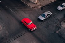 Сверху пересечения асфальтовой дороги с красным винтажным автомобилем среди современных транспортных средств в центре Кубы — стоковое фото