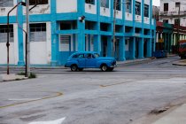 Мала вулиця з старовинним автомобілем на узбіччі між історичними барвистими будинками з барами на вікнах на Кубі. — стокове фото