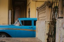 Small street with vintage car in roadside between historical colorful buildings with bars on windows in Cuba — Stock Photo
