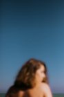 Снизу вид размытой задумчивой женщины расслабляющей на удивительном голубом небе в сумерках — стоковое фото