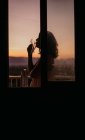 Seitenansicht einer jungen gesichtslosen Frau Silhouette Zigarettenanzündung mit herrlichem Sonnenuntergang auf verschwommenem Hintergrund — Stockfoto