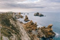 Incredibile paesaggio aereo di ripida costa rocciosa e mozzafiato oceano ondulato in giornata nuvolosa a Pielagos, Cantabria, Santander, Spagna — Foto stock