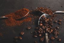 Arten von Kaffeesatz Instant und Pulver und Kaffeebohnen in Löffeln auf schwarzem Tisch — Stockfoto