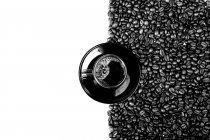 Vista superior da xícara preta de café na placa com grãos de café isolados no fundo branco — Fotografia de Stock