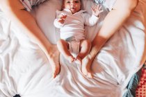 Vista superior de la cosecha bebé recién nacido en pañal acostado en la cama con la madre en casa - foto de stock