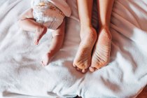 Visão superior do bebê recém-nascido na fralda deitada na cama com a mãe em casa — Fotografia de Stock