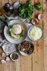 Top view fried egg on potato on wooden table with fried mushrooms grated cheese and herbs — Stock Photo
