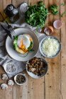 Top view fried egg on potato on wooden table with fried mushrooms grated cheese and herbs — Stock Photo
