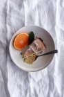De arriba apetitoso pastel dulce y mandarina naranja madura cortada y servida en plato blanco en la mesa - foto de stock