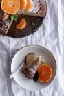 Dall'alto torta dolce appetitosa e mandarino arancione maturo tagliato e servito su piatto bianco sul tavolo — Foto stock