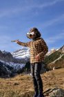Active smart boy looking away in VR glasses playing standing on stone in mountain valley — Stock Photo