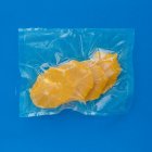 Vista superior de laranja madura descascada em saco de plástico a vácuo no fundo azul — Fotografia de Stock