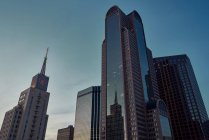 Desde abajo rascacielos modernos con cielo azul en el fondo al atardecer en Dallas, Texas, EE.UU. - foto de stock