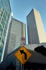 From below of road signs with big modern skyscrapers and blue sky on background — Stock Photo