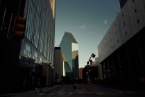 Leere Asphaltkreuzung inmitten großer Glasgebäude mit blauem Himmel im Hintergrund in der Abenddämmerung in Dallas, Texas New York — Stockfoto
