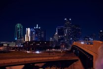 Rocked empty crossed bridges with bright colorful skyscrapers of downtown under night black sky — Stock Photo