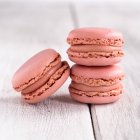 Macaron rosa gustosi impilati in pila contro la superficie bianca in legno — Foto stock