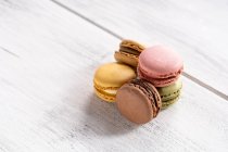 Colorful tasty macaroons stacked in pile against wooden white surface — Stock Photo