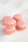Macaron rosa gustosi impilati in pila contro la superficie bianca in legno — Foto stock