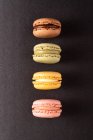 Macarons savoureux colorés affichés sur fond noir — Photo de stock