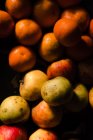 Сверху свежие сочные яблоки мандарин с гранатом и оранжевой морковью на черной поверхности при свете — стоковое фото