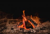 Gelbe Flammen steigen nachts aus Lagerfeuer auf Holzstücken in der Natur auf — Stockfoto