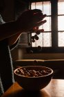 Pessoa irreconhecível agarrando cheio de avelã fresca saborosa em tigela de madeira marrom — Fotografia de Stock