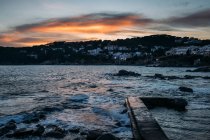 Wellen spülen alten Landungssteg unter wolkenverhangenem Sonnenuntergang in Girona, Katalonien, Spanien — Stockfoto