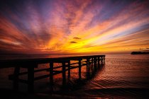 Paisagem de tirar o fôlego de cais solitário no vasto oceano sob o céu colorido brilhante no pôr do sol — Fotografia de Stock