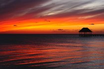 Paesaggio mozzafiato di molo solitario con cabina in vasto oceano sotto cielo colorato luminoso al tramonto — Foto stock