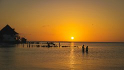 Paisagem de tirar o fôlego de casa de cais solitária no vasto oceano sob o céu colorido brilhante no pôr do sol — Fotografia de Stock
