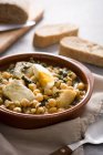 Chickpea stew with spinach and cod fish or vigil potaje on wooden table — Stock Photo