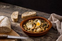 Chickpea stew with spinach and cod fish or vigil potaje on wooden table — Stock Photo