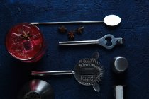 Köstlicher roter Cocktail und Barmann-Werkzeuge auf dem Tisch — Stockfoto