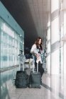 Спокойная женщина с помощью телефона в аэропорту — стоковое фото