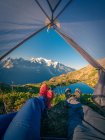 Turisti rilassati sdraiati in tenda in montagne innevate alla luce del sole — Foto stock
