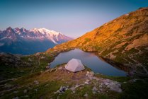 D'en haut petite tente et lac clair reflétant ciel haut dans les montagnes par temps ensoleillé à Chamonix, Mont-Blanc — Photo de stock