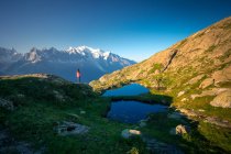 Desde arriba pequeña tienda y lago claro que refleja el cielo alto en las montañas en el día soleado en Chamonix, Mont-Blanc - foto de stock