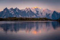Lago de cristal que refleja las montañas nevadas en el día brillante - foto de stock