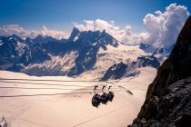 De cima cobertas cabines movendo-se para baixo teleférico em branco montanhas nevadas em dia nublado brilhante em Chamonix, Mont-Blanc — Fotografia de Stock