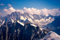 Picos de montaña blancos y agudos en la nieve que sube al cielo nublado - foto de stock