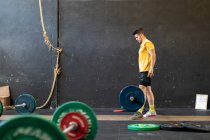 Мускулистый парень поднимает штангу в современном спортзале — стоковое фото