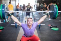 Muscular cara levantando barbell no ginásio moderno — Fotografia de Stock
