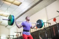 Musclé levant haltère dans la salle de gym moderne — Photo de stock