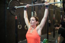 Femme levant haltère dans la salle de gym — Photo de stock