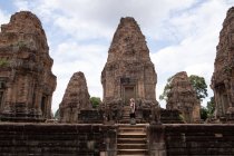 Side view of unrecognizable woman looking at ancient ruins of religious Hindu temple of Angkor Wat in Cambodia — Stock Photo