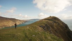 Back view of unrecognizable woman enjoying wonderful nature landscape and sea while standing on cliff in Ireland looking away — Stock Photo